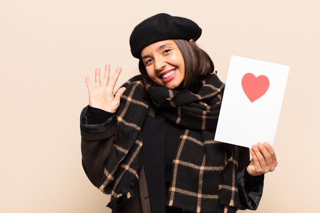 Mujer bonita joven sosteniendo una tarjeta de corazón