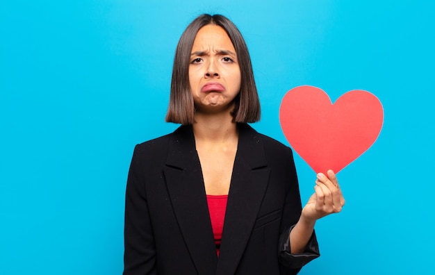 Mujer bonita joven sosteniendo una tarjeta de corazón