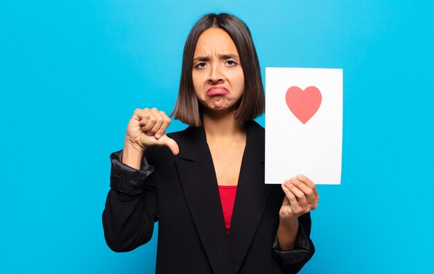 Mujer bonita joven sosteniendo una tarjeta de corazón