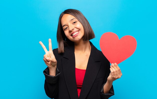 Mujer bonita joven sosteniendo una tarjeta de corazón