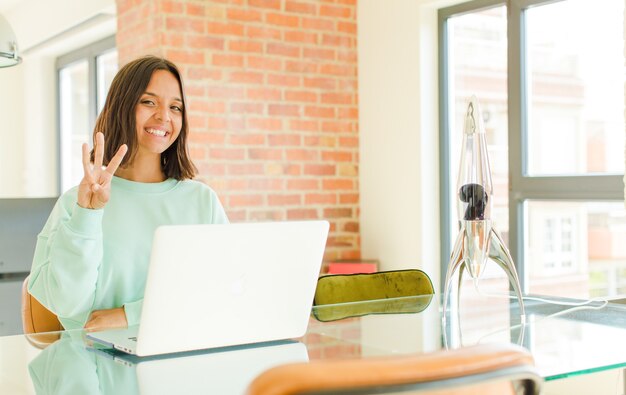 Mujer bonita joven trabajando, sonriendo y mirando amistosamente, mostrando el número uno o el primero con la mano hacia adelante, contando hacia atrás