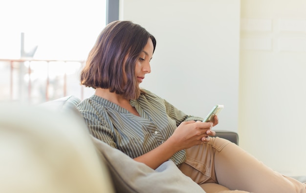 Mujer bonita joven usando su teléfono en casa