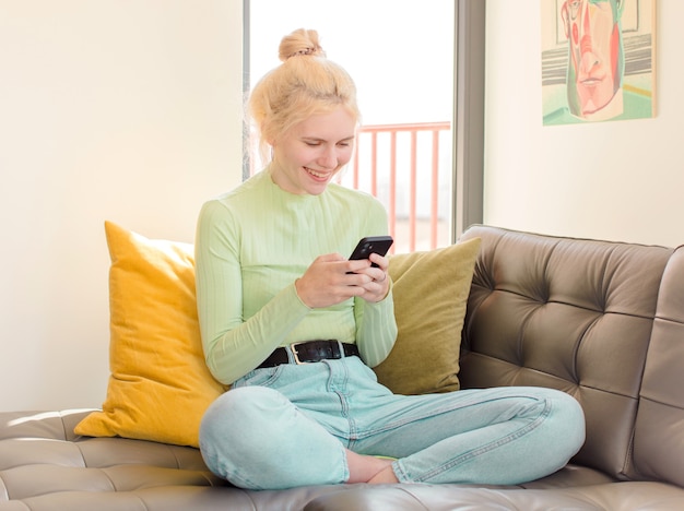 Mujer bonita joven usando su teléfono en casa