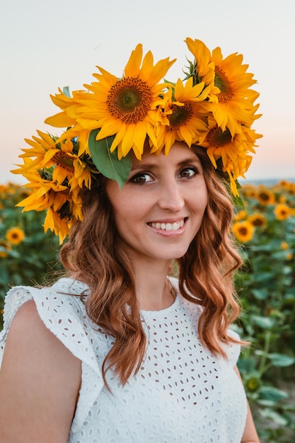 Mujer bonita joven en vestido blanco en el floreciente campo de girasoles