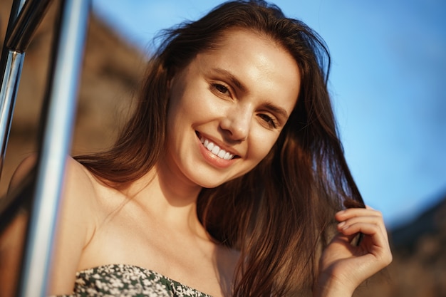 Mujer bonita joven en vestido floral posando en yate en el mar