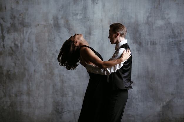 Foto mujer bonita joven en vestido negro y hombre bailan tango