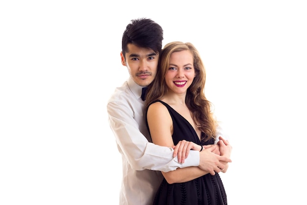 Mujer bonita joven en vestido de noche negro y hombre guapo con cabello oscuro en camisa con corbatín