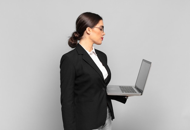 Mujer bonita joven en vista de perfil mirando para copiar espacio por delante, pensando, imaginando o soñando despierto. concepto de laptop