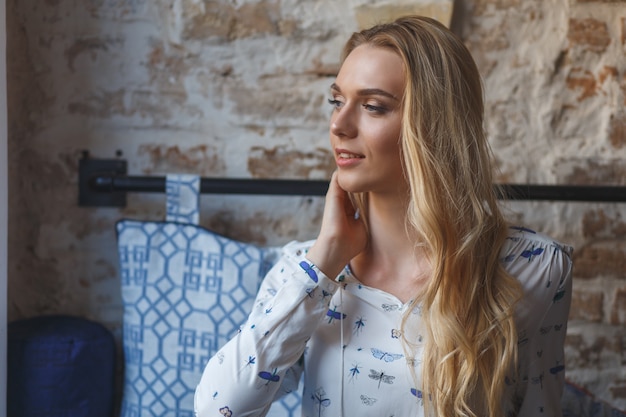 Mujer bonita joven vistiendo blusa blanca descansando en el sofá en el café