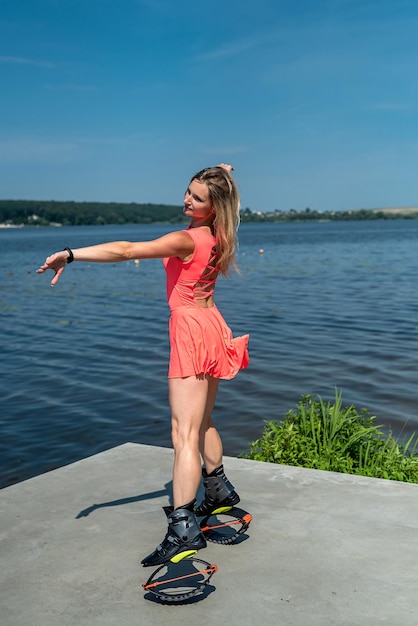 Mujer bonita joven en zapatos de salto kangoo haciendo ejercicio cerca del lago de la ciudad Concepto de deportes y salud