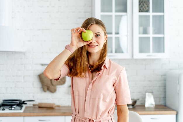 Foto mujer bonita juguetona posando con comida saludable mujer hermosa alegre mirando a la cámara con manzana