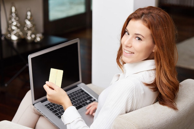 Mujer bonita con laptop en sofá