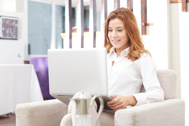 Mujer bonita con laptop en sofá