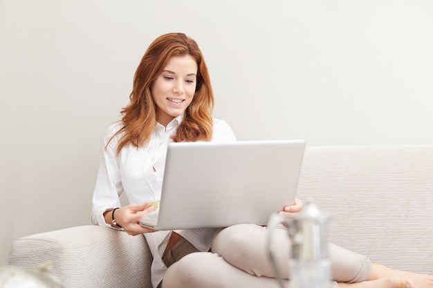 Mujer bonita con laptop en sofá