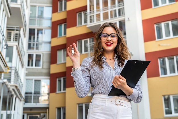 Mujer bonita con llaves de casa nueva. Concepto de venta