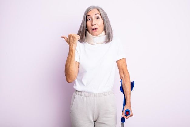 Mujer bonita mayor que parece asombrada con incredulidad. concepto de accidente de muleta y collar