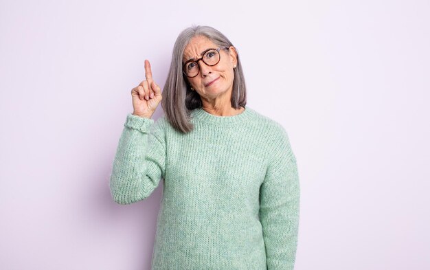 mujer bonita mayor que se siente como un genio levantando el dedo con orgullo en el aire después de darse cuenta de una gran idea, diciendo eureka