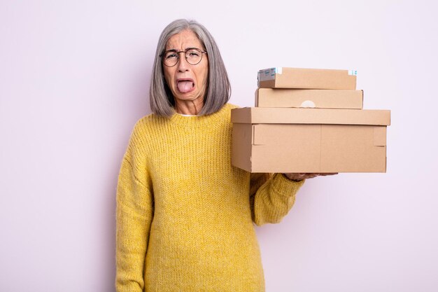 Mujer bonita mayor que se siente disgustada e irritada y con la lengua fuera. concepto de almacenamiento