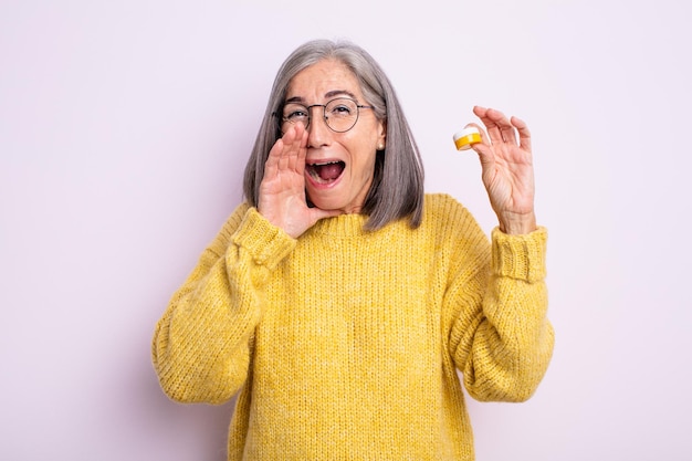 Mujer bonita mayor que se siente feliz, dando un gran grito con las manos al lado de la boca. concepto de lentes de contacto