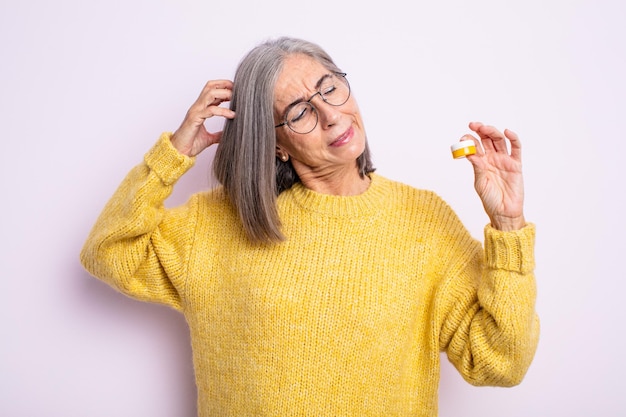 Mujer bonita mayor que se siente perpleja y confundida, rascándose la cabeza. concepto de lentes de contacto