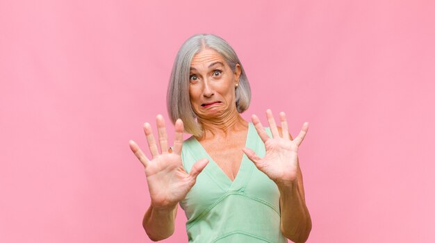 Mujer bonita de mediana edad apuntando a sí misma con una mirada confundida y burlona, conmocionada y sorprendida de ser elegida