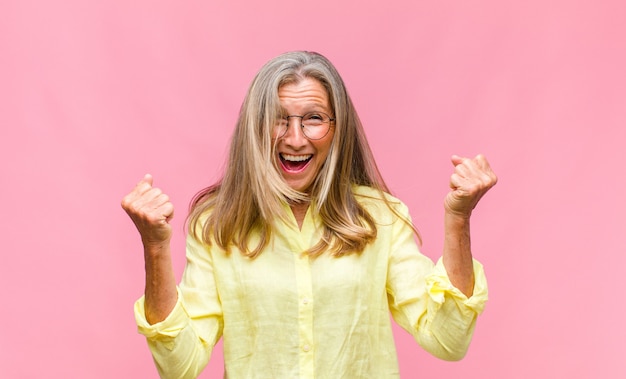 Mujer bonita de mediana edad con camisa amarilla y anteojos en azul