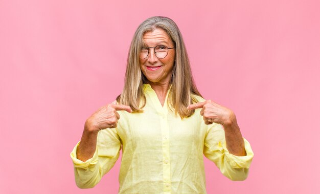 Mujer bonita de mediana edad con camisa amarilla y anteojos en rosa