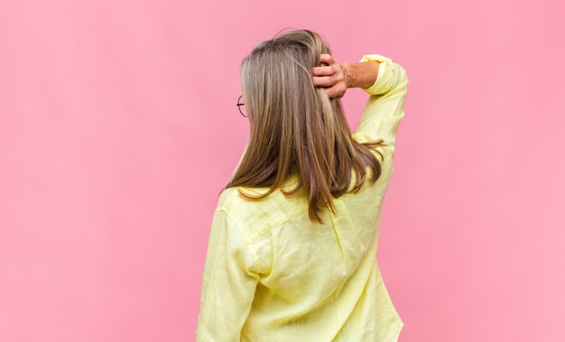 Mujer bonita de mediana edad con camisa amarilla en vista posterior