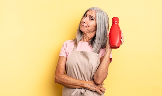 Mujer bonita de mediana edad encogiéndose de hombros, sintiéndose confusa e insegura. concepto de salsa de tomate