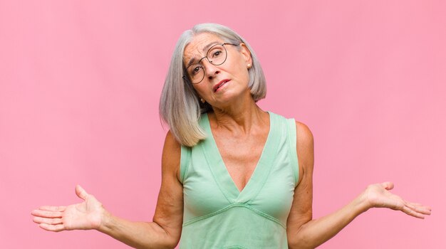 Mujer bonita de mediana edad levantando la palma de la mano a la frente pensando Ups, después de cometer un error estúpido o recordar, sentirse tonto