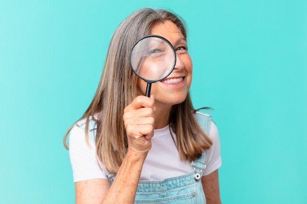 Mujer bonita de mediana edad con una lupa. concepto de búsqueda