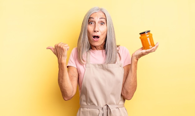 Mujer bonita de mediana edad mirando asombrado con incredulidad. Mermelada de durazno