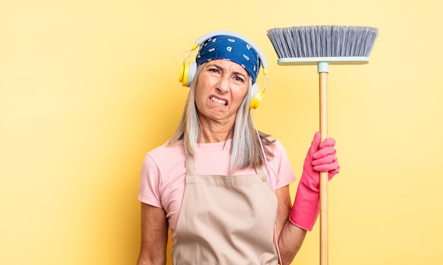 Mujer bonita de mediana edad que parece desconcertado y confundido. concepto de hogar y escoba