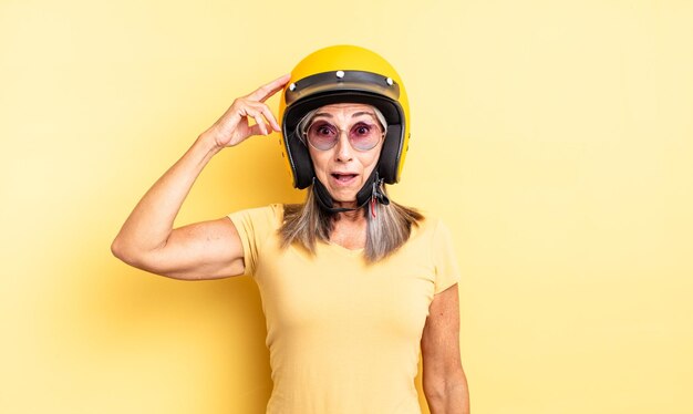 Mujer bonita de mediana edad que parece feliz, asombrada y sorprendida. concepto de casco de moto