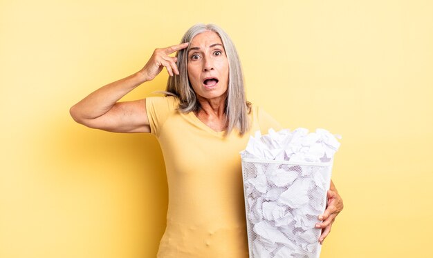 Mujer bonita de mediana edad que parece feliz, asombrada y sorprendida. concepto de falla de bolas de papel