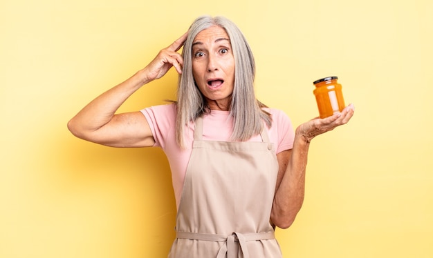 Mujer bonita de mediana edad que parece feliz, asombrada y sorprendida. Mermelada de durazno