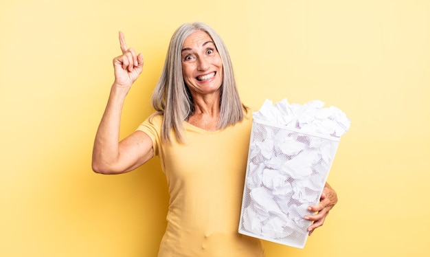 Mujer bonita de mediana edad que se siente como un genio feliz y emocionado después de realizar una idea. concepto de falla de bolas de papel