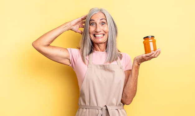 Mujer bonita de mediana edad que se siente estresada, ansiosa o asustada, con las manos en la cabeza. Mermelada de durazno