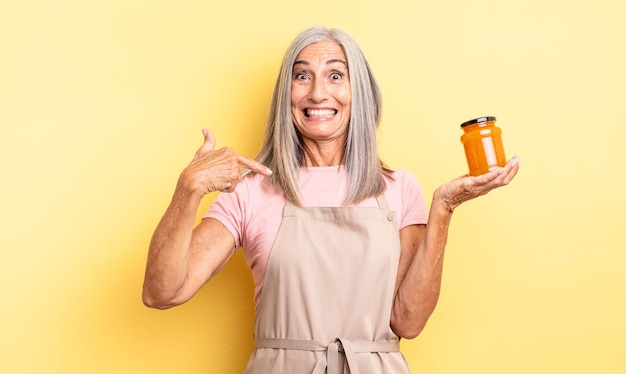 Mujer bonita de mediana edad que se siente feliz y apunta a sí misma con un entusiasmo. Mermelada de durazno