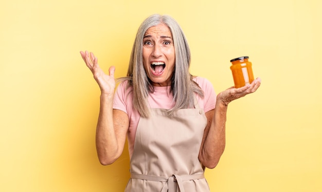 Mujer bonita de mediana edad que se siente feliz y asombrada por algo increíble. Mermelada de durazno