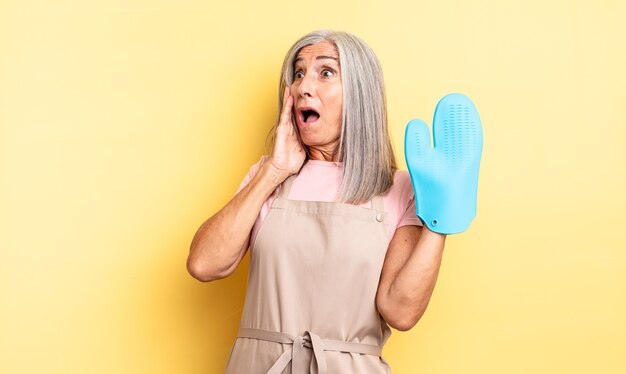 Mujer bonita de mediana edad que se siente feliz, emocionada y sorprendida. concepto de manopla de horno