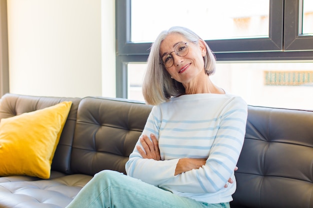 Mujer bonita de mediana edad riendo felizmente con los brazos cruzados, con una pose relajada, positiva y satisfecha