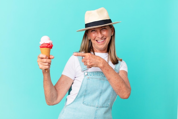 Mujer bonita de mediana edad con sombrero y sosteniendo un helado. concepto de verano