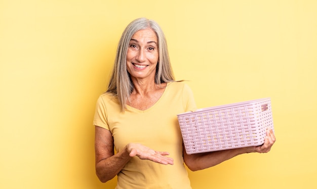 Mujer bonita de mediana edad sonriendo alegremente, sintiéndose feliz y mostrando un concepto. concepto de cesta vacía