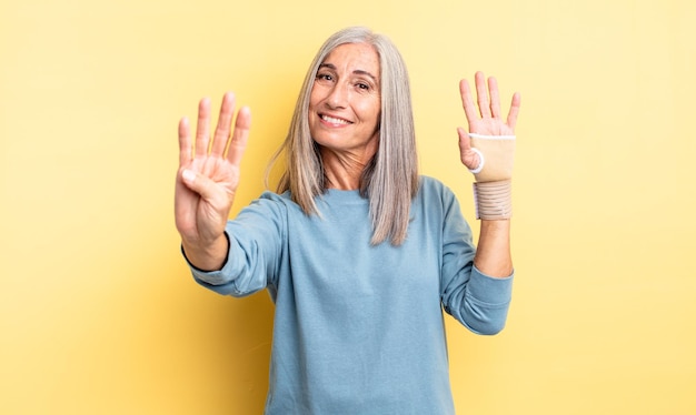 Mujer bonita de mediana edad sonriendo y mirando amigable, mostrando el número cuatro. concepto de vendaje de mano