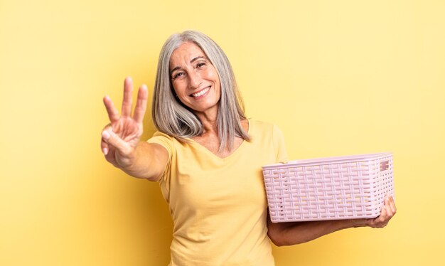 Mujer bonita de mediana edad sonriendo y mirando amigable, mostrando el número tres. concepto de cesta vacía