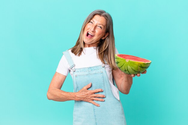 Mujer bonita de mediana edad sosteniendo una rodaja de sandía