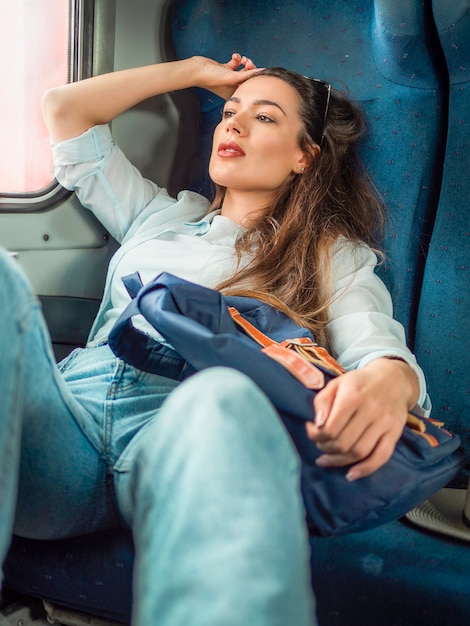 Mujer bonita mirando por la ventana en un tren viajando solo