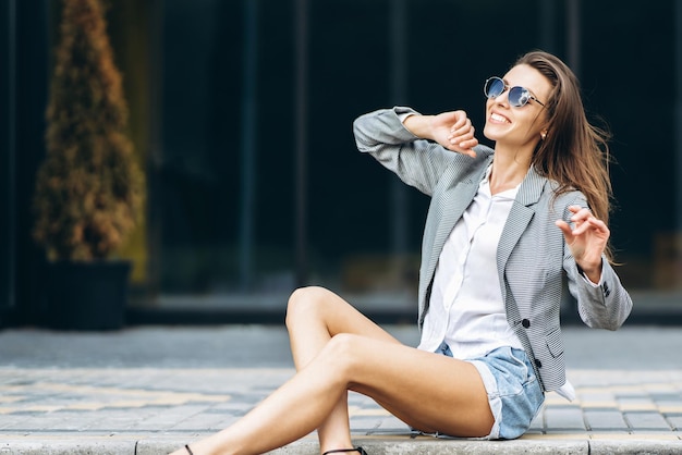 Mujer bonita de moda sentada en la calle de la ciudad