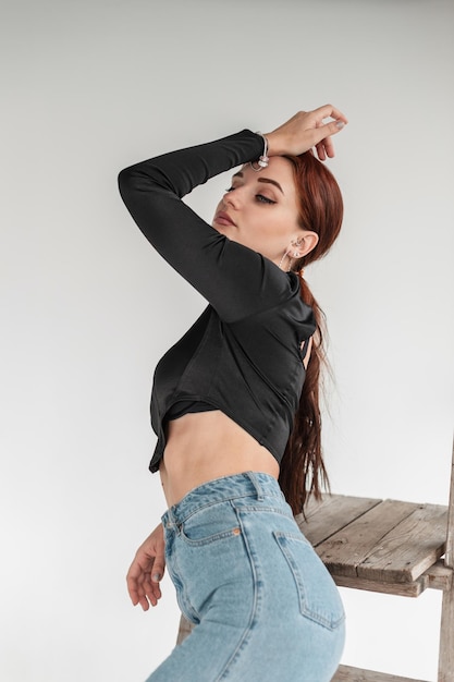 Mujer bonita modelo pelirroja en ropa casual de mezclilla posa en el interior